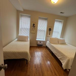 two beds in a room with two windows at Harlem House in New York