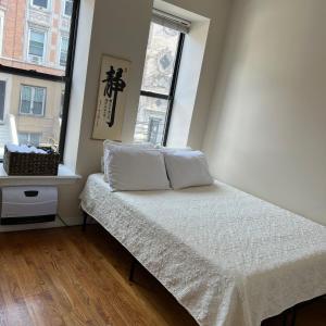 a bed in a room with two windows at Harlem House in New York