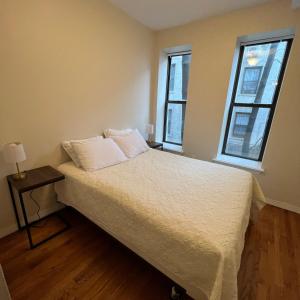 a bed in a room with two windows at Harlem House in New York