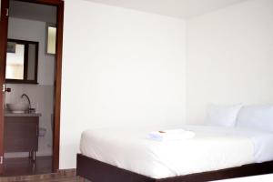 1 dormitorio con cama blanca y espejo en Hotel Villa Isabel, en Pasto