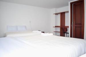 um quarto com 2 camas brancas e uma porta aberta em Hotel Villa Isabel em Pasto