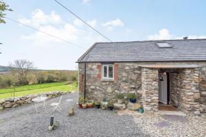 a stone cottage with a door and a patio at Celyn Farm Cottage in Cwm-y-glo