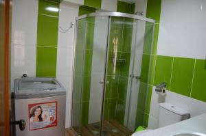 y baño con ducha y azulejos verdes. en Hermoso departamento confortable y estratégico en Sucre