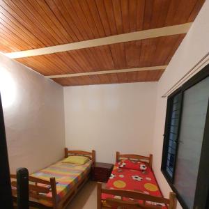 sypialnia z 2 łóżkami i drewnianym sufitem w obiekcie Villas de Santa Ana w mieście Guamo