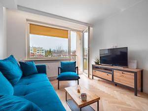 salon z niebieską kanapą i telewizorem z płaskim ekranem w obiekcie Apartament Bursztynowy Nowy w mieście Sopot