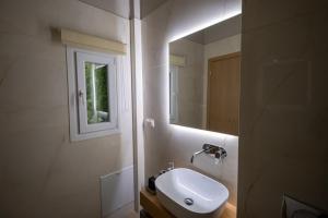 La salle de bains est pourvue d'un lavabo blanc et d'un miroir. dans l'établissement Elia Didotou City Apartments, à Athènes