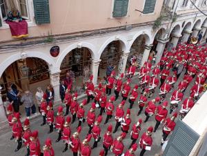 Un gruppo di uomini in uniforme rossa che camminano per strada di Piccolo Centrale a Città di Corfù