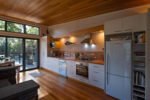 a kitchen with white appliances and a wooden ceiling at Adventure Bay Beach House in Adventure Bay