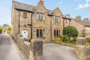 an old stone house with a stone wall at Corner Cottage in Bakewell