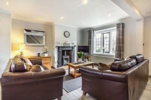 a living room with two leather chairs and a fireplace at Corner Cottage in Bakewell