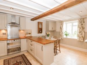 una cocina con armarios blancos y una isla de cocina en Bonnings Cottage, en Ilminster