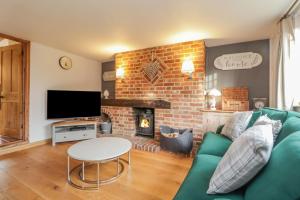 a living room with a green couch and a fireplace at 1 Forge Cottages, On the Green in Bearsted