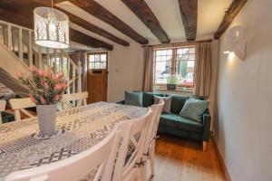 a dining room with a table and a green couch at 1 Forge Cottages, On the Green in Bearsted