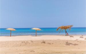 tre ombrelloni di paglia su una spiaggia con l'oceano di Alessidamo Bilo a Metaponto