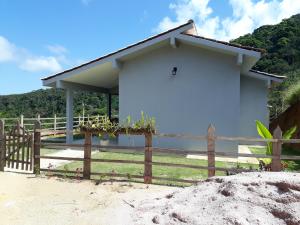 ein weißes Haus mit einem Zaun davor in der Unterkunft Chalé Privilégio in Rio Prêto