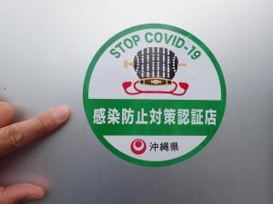 a person holding up a stop cowlitz sticker at Smilax Kurichi in Uruma