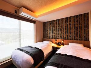 two beds in a room with a window at Rinn Gion Kenninji in Kyoto