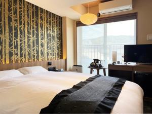 a bedroom with a bed and a tv and a window at Rinn Gion Kenninji in Kyoto