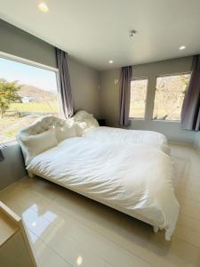 a large white bed in a bedroom with a large window at HANA TOYA in Lake Toya