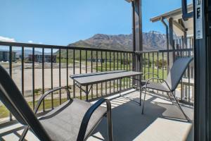 a balcony with a table and chairs and mountains at Toru Executive Apartment in Queenstown