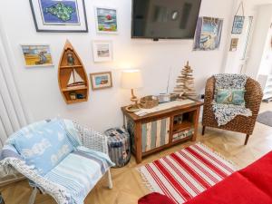 a living room with two chairs and a tv at White Haven in Sandown