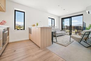 eine Küche und ein Wohnzimmer mit einem Sofa und einem Tisch in der Unterkunft Toru Top Floor Apartment - Brand New & Convenient in Queenstown