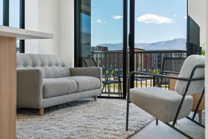 ein Wohnzimmer mit einem Sofa und einem Stuhl in der Unterkunft Toru Top Floor Apartment - Brand New & Convenient in Queenstown