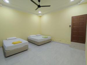 two beds in a room with a ceiling fan at Evergreen Xperience Guest House in Kuala Kubu Baharu