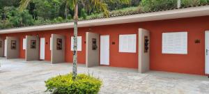 a red building with white doors and a palm tree at Estância Canaã Atibaia in Atibaia