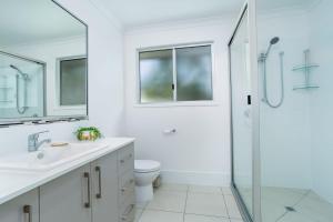 a white bathroom with a shower and a toilet at 25 Cooloola Drive Rainbow Beach in Rainbow Beach +10 photos