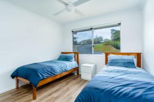 two beds in a bedroom with a window at 25 Cooloola Drive Rainbow Beach in Rainbow Beach