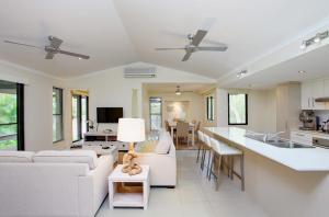 a living room with white furniture and a kitchen at 6 Orania Court Rainbow Shores in Rainbow Beach
