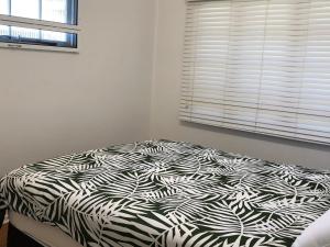 a black and white bed in a bedroom with a window at 9 Indigo Avenue Rainbow Beach in Rainbow Beach