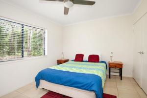 a white bedroom with a bed and a window at 18 Naiad Court Rainbow Shores in Rainbow Beach