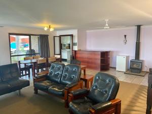 ein Wohnzimmer mit Ledersesseln und ein Esszimmer in der Unterkunft 42 Rumbalara Avenue Rainbow Beach in Rainbow Beach