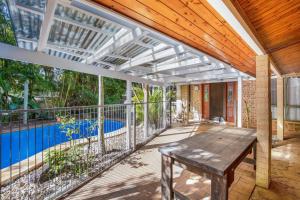 an outdoor patio with a wooden table and a swimming pool at Amaroo Rainbow Shores in Rainbow Beach