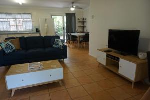 a living room with a couch and a flat screen tv at 11 Bomburra Court Rainbow Beach in Rainbow Beach