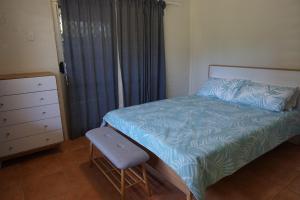 a bedroom with a bed and a chair and a dresser at 11 Bomburra Court Rainbow Beach in Rainbow Beach