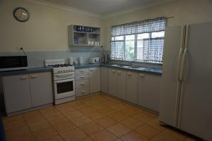 a kitchen with white cabinets and a stove and a refrigerator at 11 Bomburra Court Rainbow Beach in Rainbow Beach