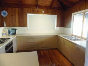 a kitchen with wooden cabinets and a sink and a window at 33 Cooloola Drive Rainbow Beach in Rainbow Beach