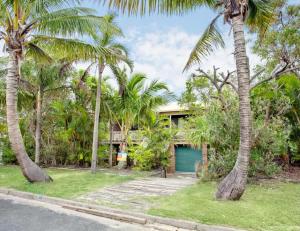 a house with palm trees and a blue garage at 33 Cooloola Drive Rainbow Beach in Rainbow Beach