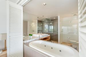 a white bathroom with a tub and a sink at Unit 101 Plantation Resort Rainbow Beach in Rainbow Beach +3 photos