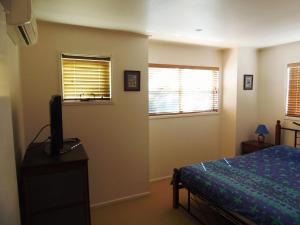 a bedroom with a bed and a tv and two windows at COOLAMAINE 2 Rainbow Beach in Rainbow Beach