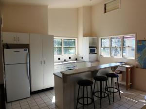 a kitchen with white cabinets and bar stools at COOLAMAINE 2 Rainbow Beach in Rainbow Beach