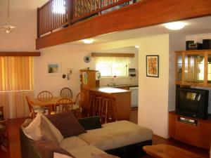 a living room with a couch and a kitchen at Sand Piper Cottage Rainbow Beach in Rainbow Beach