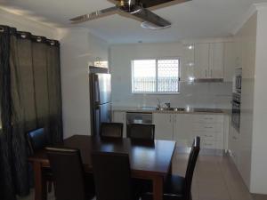 a kitchen with a table and chairs and a refrigerator at Palmgrove 2 Rainbow Beach in Rainbow Beach