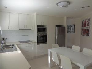 a kitchen with white cabinets and a white table at Palmgrove 1 Rainbow Beach in Rainbow Beach