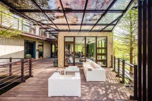a glass roofed porch with white furniture on a wooden deck at 灣曲時尚會館 Watch House in Dongshan