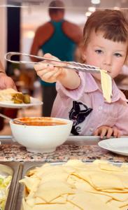 un niño pequeño está preparando comida en una cocina en Abaash Hotel Afon, en Novi Afon