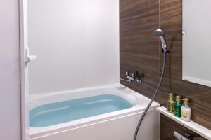 uma banheira na casa de banho com um chuveiro em HOTEL Gran Arenaホテルグランアリーナ em Okinawa City